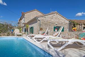 a villa with a swimming pool with chairs and a house at Holiday Home Jurko in Rakalj