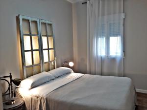 1 dormitorio con 1 cama blanca grande y ventana en Urban Suites El Postigo, en Córdoba
