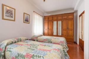 a bedroom with two beds and a wooden cabinet at Apartamento Milagros 110 m2 in Málaga