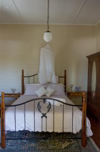 a bedroom with a bed with white sheets and a lamp at Maddies of Bolwarra in Maitland