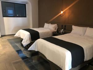 a hotel room with two beds and a window at Hotel Isabel in Puebla