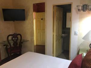 Habitación con cama, TV y puerta en Hotel Elena, en Puebla