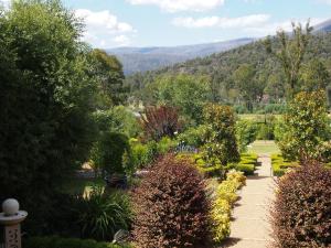 a garden with bushes and trees and mountains in the background at Delderfield Villas Adults Retreat in Marysville
