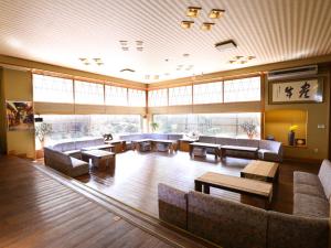 a large room with couches and tables and windows at Hotel Housei in Yamanouchi
