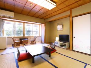 a living room with a table and chairs and a tv at Hotel Housei in Yamanouchi