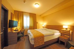 a hotel room with a bed and a desk and a television at Hotel Saint Fiacre in Bourscheid