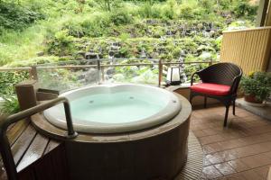 a bath tub sitting on a deck with a chair at Hotel Futaba in Yuzawa