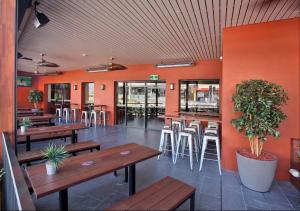 a restaurant with wooden tables and chairs and orange walls at Kingsgrove Hotel in Sydney