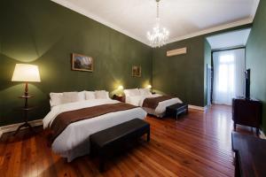 2 camas en un dormitorio con paredes verdes y suelo de madera en Hotel del Casco en San Isidro