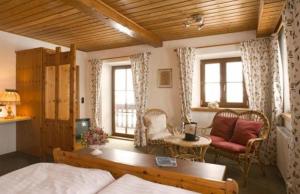 a living room with a bed and a couch and windows at Landhotel Binderhäusl Garni in Inzell