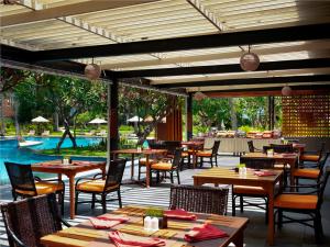 a restaurant with tables and chairs and a pool at Mangsit Suites by Holiday Resort Lombok in Mangsit