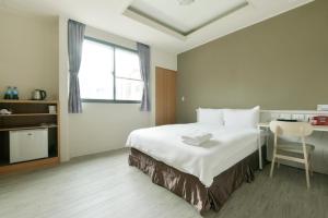 a bedroom with a white bed and white walls at Raise Hotel Taichung in Taichung