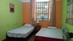 um pequeno quarto com 2 camas e uma janela em Hostal Virrey & Tours em Trujillo