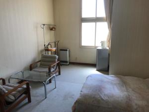 um quarto com uma cama, uma cadeira e uma janela em Yamatoya em Nozawa Onsen