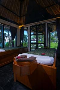 a bedroom with a large bed and windows at Mangsit Suites by Holiday Resort Lombok in Mangsit