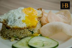 a plate of food with an egg and rice and cucumbers at H Benjamin Residence in Kampong Kundassan