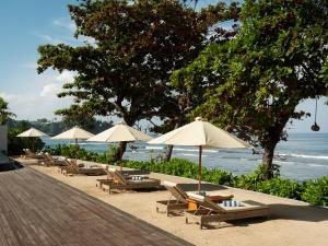 a group of chairs and umbrellas on a beach at Mangsit Suites by Holiday Resort Lombok in Mangsit