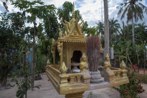 una mujer sentada en un santuario de oro en un jardín en Chansor Community Homestay 12, en Siem Reap