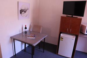 Habitación con mesa, TV y mesa pequeña con botella de vino. en Childers Gateway Motor Inn, en Childers