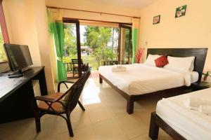 a bedroom with two beds and a desk and a television at Pranmanee Beach Resort in Sam Roi Yot