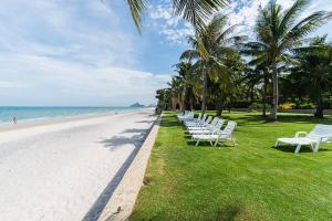 a row of white benches sitting on the beach at Marrakesh Huahin 4bedrooms suite with Jacuzzi 208 in Hua Hin