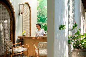 a woman sitting at a counter in a room at Avani Plus Samui Resort in Taling Ngam Beach