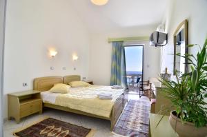 - une chambre avec un lit et une grande fenêtre donnant sur l'océan dans l'établissement Hotel Olympiada, à Vráchos