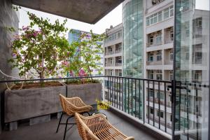 a balcony with chairs and a tree and buildings at Tropical House Apartment Da Nang in Da Nang