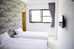 two beds in a room with a window at 108 House Inn in Tainan