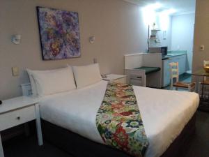 a hotel room with a large bed and a kitchen at Colonial Lodge Motel in Taupo