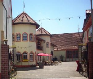 ein großes Gebäude mit einer Terrasse mit Tischen und Stühlen in der Unterkunft Weinschlößchen im Weingut Roos in Ilbesheim