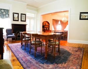 a dining room with a table and chairs on a rug at Bauhenia Guesthouse in Potchefstroom