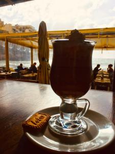 a cup of tea sitting on a table with a cookie at Moby Dick Xlendi Holiday Apartments in Xlendi