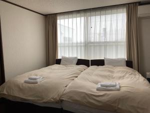a bedroom with a bed with two towels on it at Mountain View Lodge in Furano