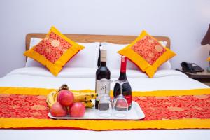 a tray of fruit and wine bottles on a bed at The Boudha Inn in Kathmandu