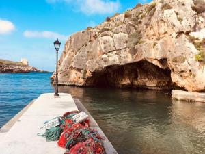 a boat in the water next to a cave at Moby Dick Xlendi Holiday Apartments in Xlendi +16 photos