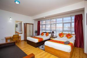 a hotel room with two beds and a window at The Boudha Inn in Kathmandu