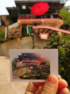 una mano che tiene in mano la foto di una casa con un ombrello rosso di Lungphut Homestay a Chiang Mai