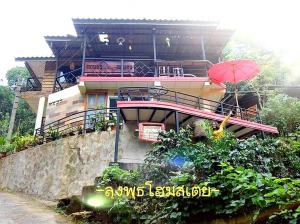 a house with a balcony and a red umbrella at Lungphut Homestay in Chiang Mai