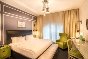 Habitación de hotel con cama y silla verde en Dondar Hotel Formula 1 View en Bakú