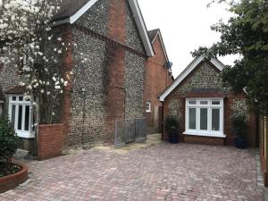 a brick house with a brick driveway in front of it at The Coach House 75 Epsom Road in Guildford