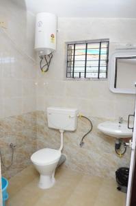 a bathroom with a toilet and a sink at Green Woods Homestay in Kodaikānāl