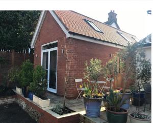 a small brick house with potted plants in front of it at The Coach House 75 Epsom Road in Guildford