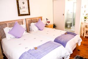 - 2 lits dans une chambre avec des oreillers violets dans l'établissement On the Bay, à Port Elizabeth