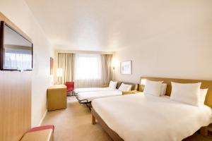 a hotel room with a large white bed and a couch at Novotel Atria Nimes Centre in Nîmes