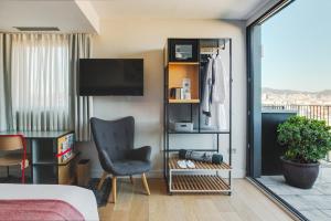 a room with a bed and a chair and a television at Hotel Brummell in Barcelona