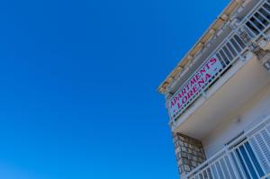 a building with a balcony and blue sky in the background at Apartments Lorena Mljet in Pomena
