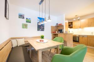 uma cozinha e sala de jantar com uma mesa de madeira e cadeiras verdes em Ferienwohnungen Alpentraum - Mäusle em Oberstdorf