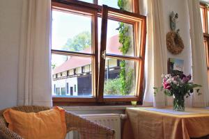 Zimmer mit einem Tisch und einem Fenster mit einer Blumenvase in der Unterkunft Berghof Lichtenhain in Lichtenhain