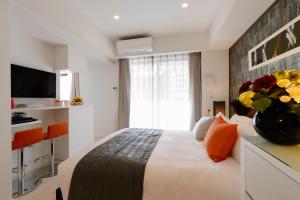 una habitación de hotel con una cama y un jarrón de flores en Oakwood Apartments Minami Azabu en Tokio